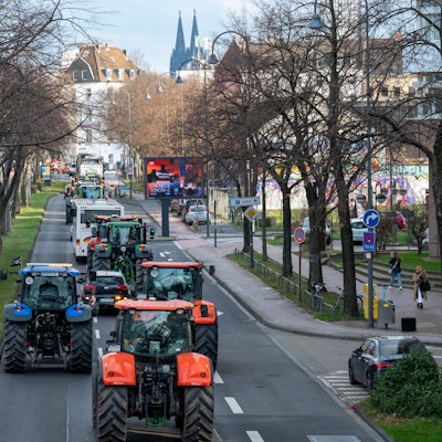 Traktoren fahren eine Straße in Köln entlang, im Hintergrund ist der Dom zu sehen.