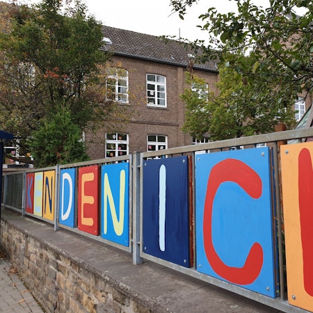 Das Foto zeigt das Wort „Kendenich“ in bunten Lettern am Zaun der Grundschule.
