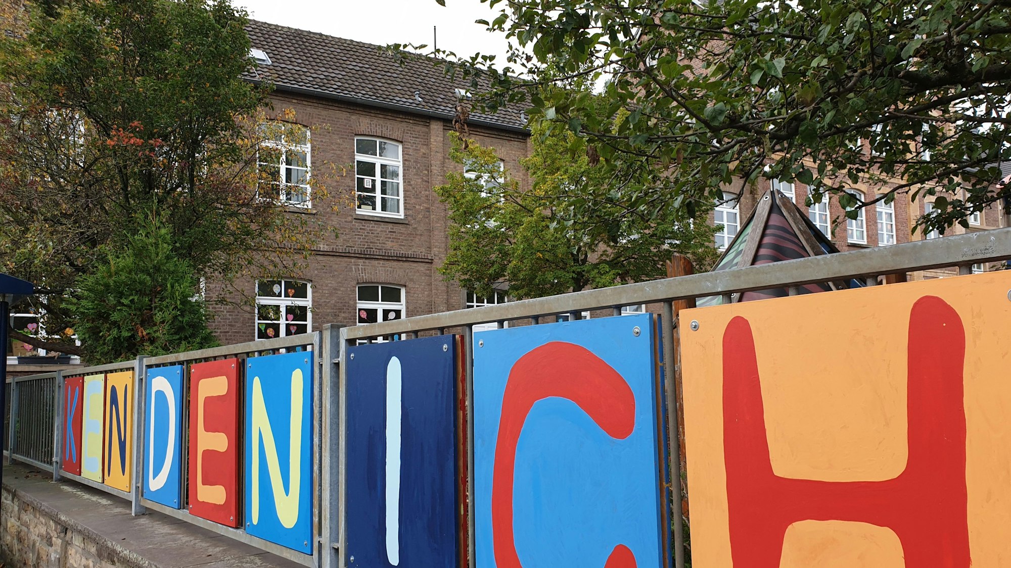 In bunten Lettern prangt der Schriftzug „Kendenich“ am Zaun vor dem Schulgebäude.
