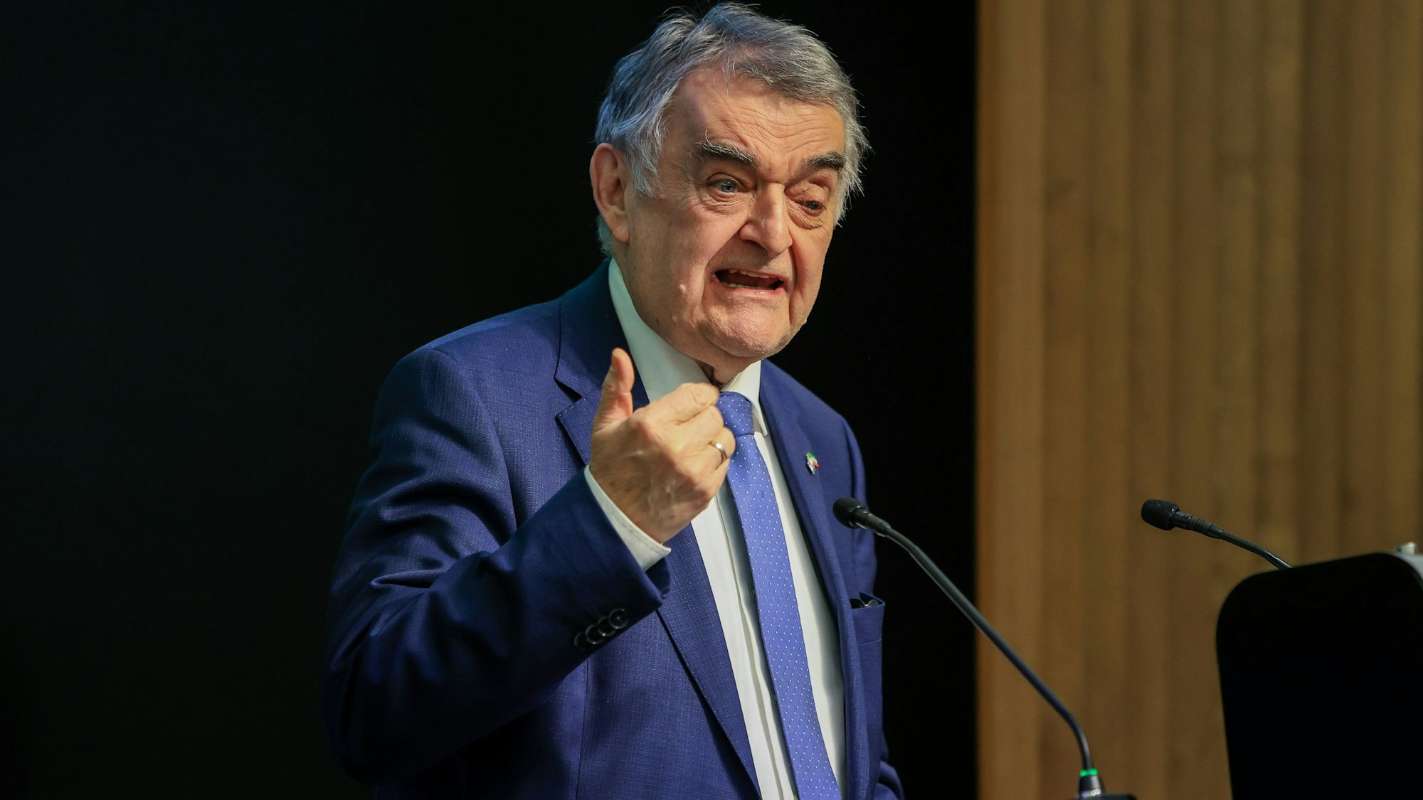 Mann höheren Alters mit einem blauen Anzug, weißem Hemd und blauer Krawatte