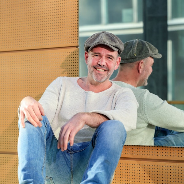 Heinz-Wilhelm Esser guckt in die Kamera und lacht. Er hat eine Mütze auf.