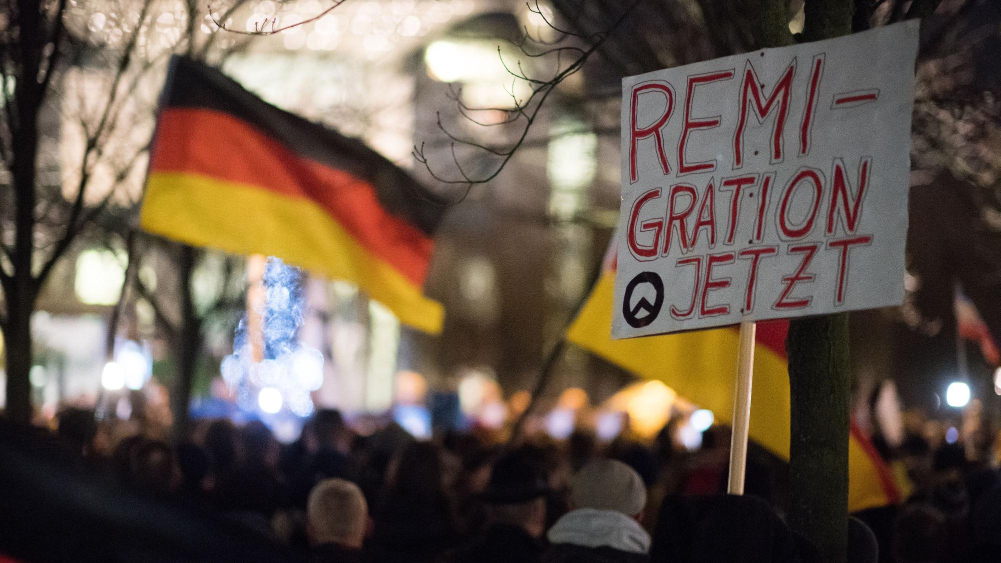 Teilnehmer einer Mahnwache rechter Gruppen mit einem Schild mit der Aufschrift „Remigration Jetzt“ (Archivbild)