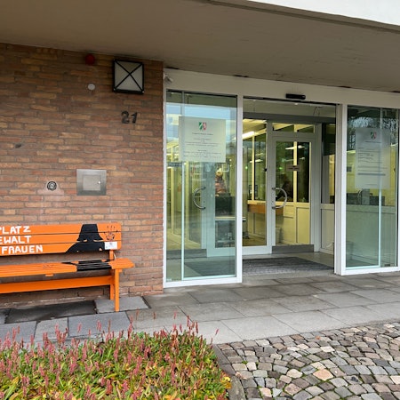 Am Eingang zum Bensberger Amtsgericht steht eine orangefarbene Bank mit der Aufschrift  „Kein Platz für Gewalt gegen Frauen“.