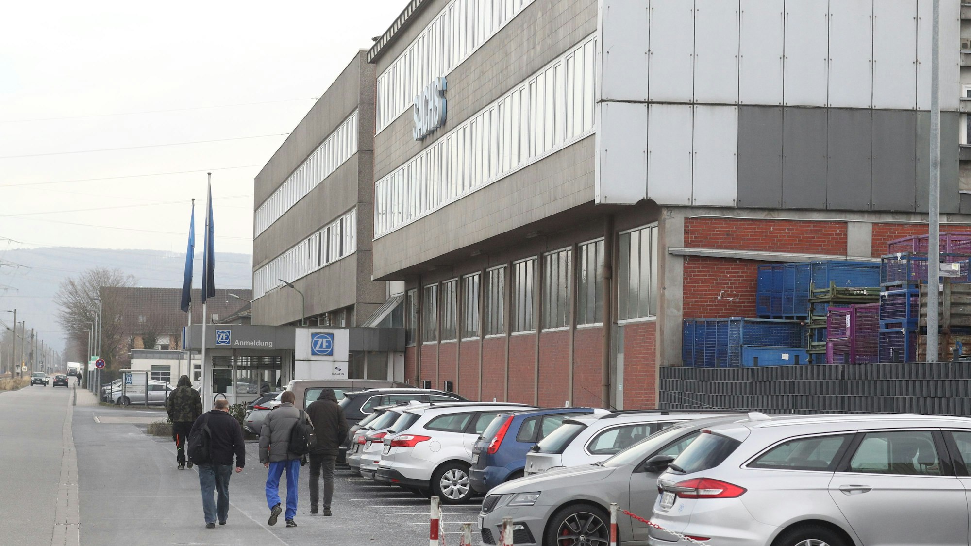 Vier Männer gehen vom Parkplatz zum Eingangstor des ZF-Werks.