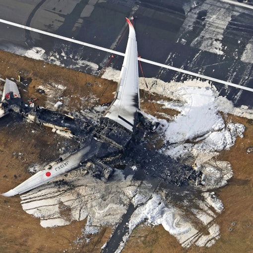 Der ausgebrannte Airbus A350 der japanischen Fluggesellschaft Japan Airlines kurz nach dem Zusammenstoß mit einer Bombardier DHC-8 der japanischen Küstenwache. Das Flugzeugwrack ist komplett verbrannt, nur noch Reste der Flügel sind zu erkennen.