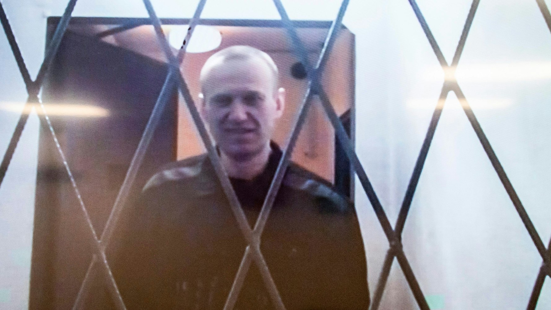 Alexej Nawalny ist auf einem Fernsehbildschirm zu sehen, als er per Video aus einem Gerichtssaal erscheint.