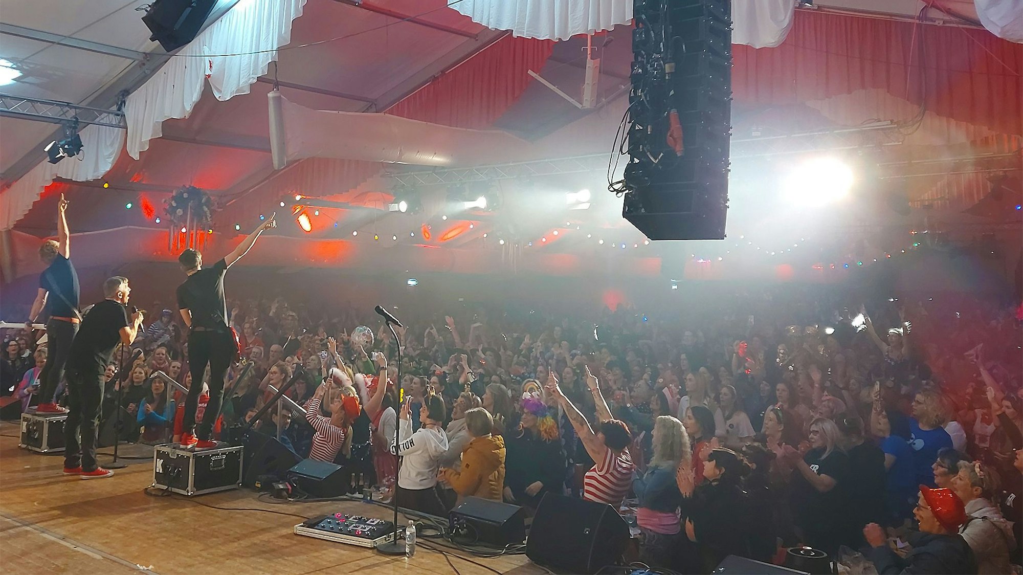 Viele Fans stehen vor der Bühne und jubeln, während die Karnevalsband Kasalla spielt.