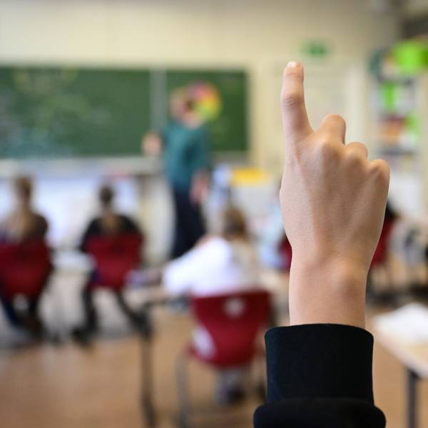 Kinder zeigen in einer Schulklasse auf.