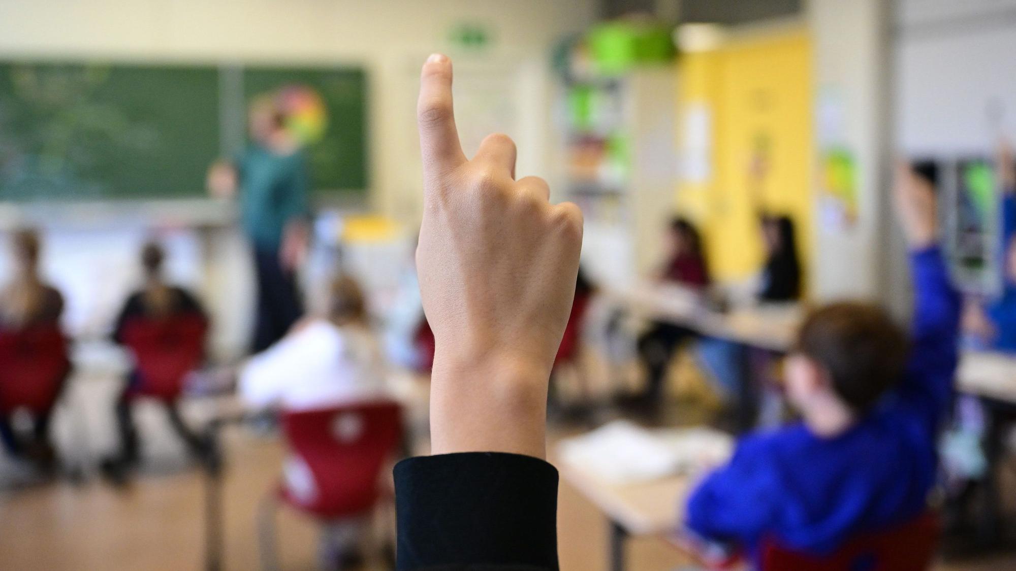 Kinder zeigen in einer Schulklasse auf.