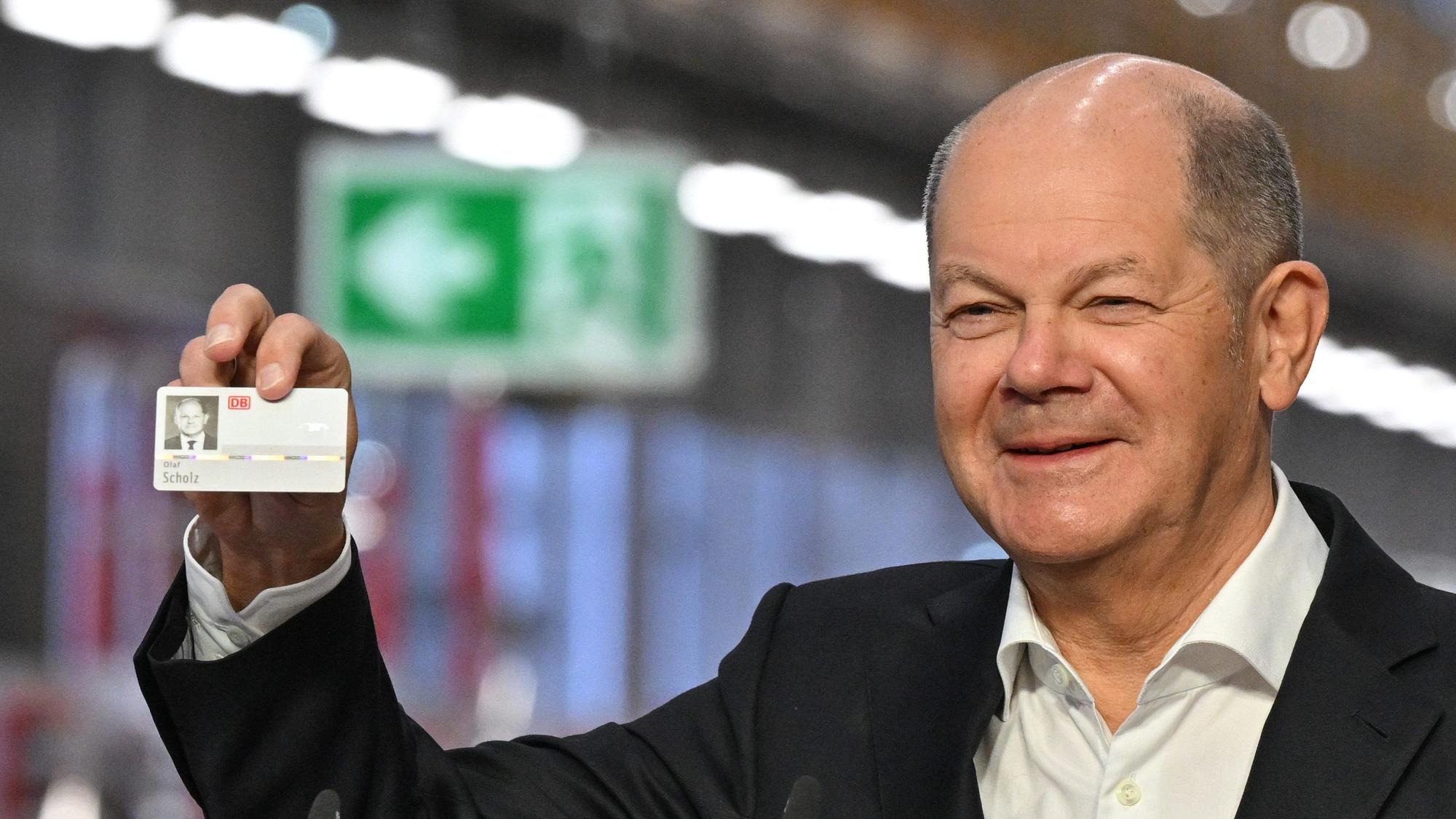 Cottbus: Bundeskanzler Olaf Scholz (SPD) freut sich über einen Mitarbeiterausweis, den er zur Eröffnung vom DB-Instandhaltungswerk geschenkt bekommen hat.