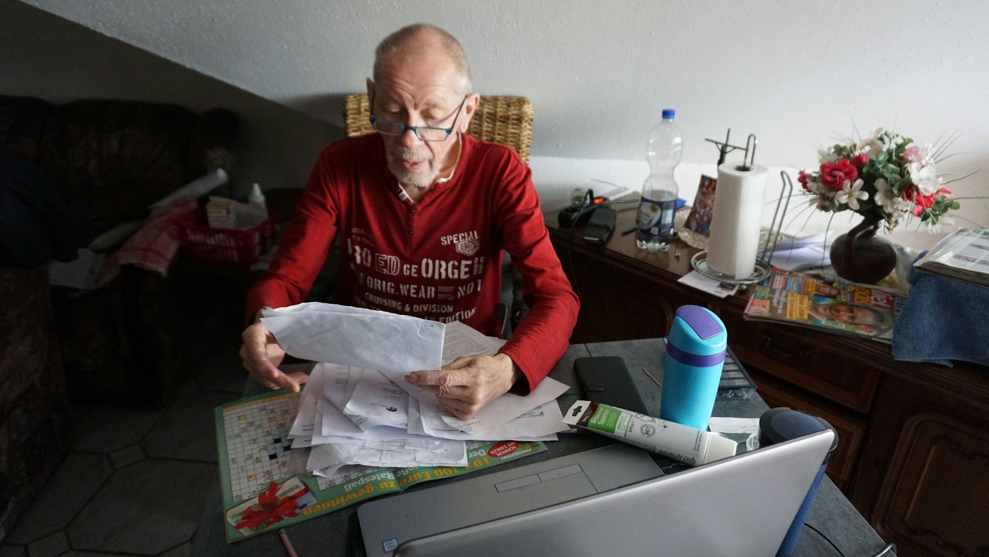 Josef Schwingeler sitzt inmitten seiner Wohnung und liest in seinen Papieren.