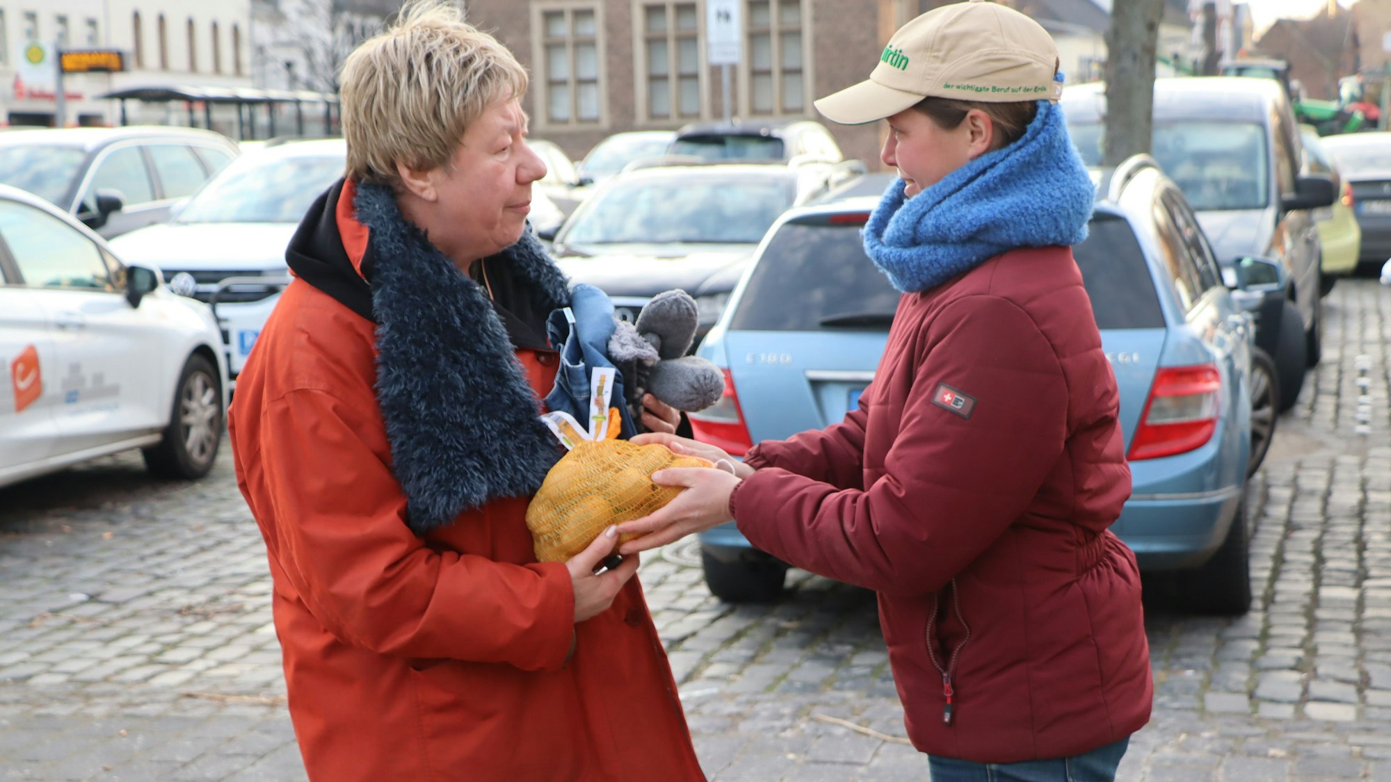 Eine Landwirtin gibt einer Frau ein Säckchen Kartoffeln.