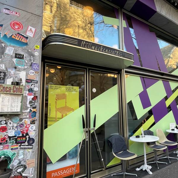 Die Front eines Cafés ist mit breiten lila und lindgrün-farbenen Streifen beklebt.