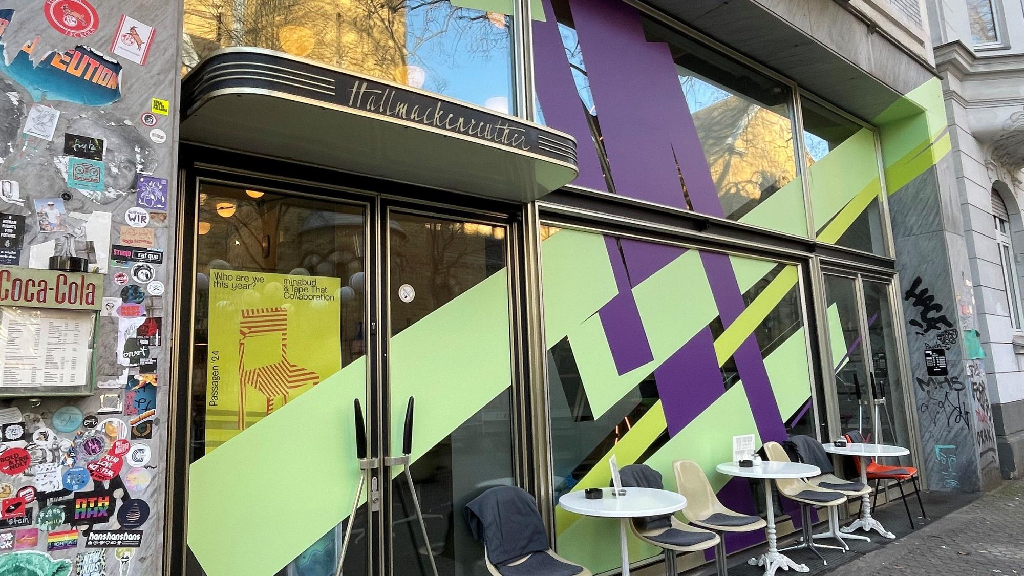 Die Front eines Cafés ist mit breiten lila und lindgrün-farbenen Streifen beklebt.