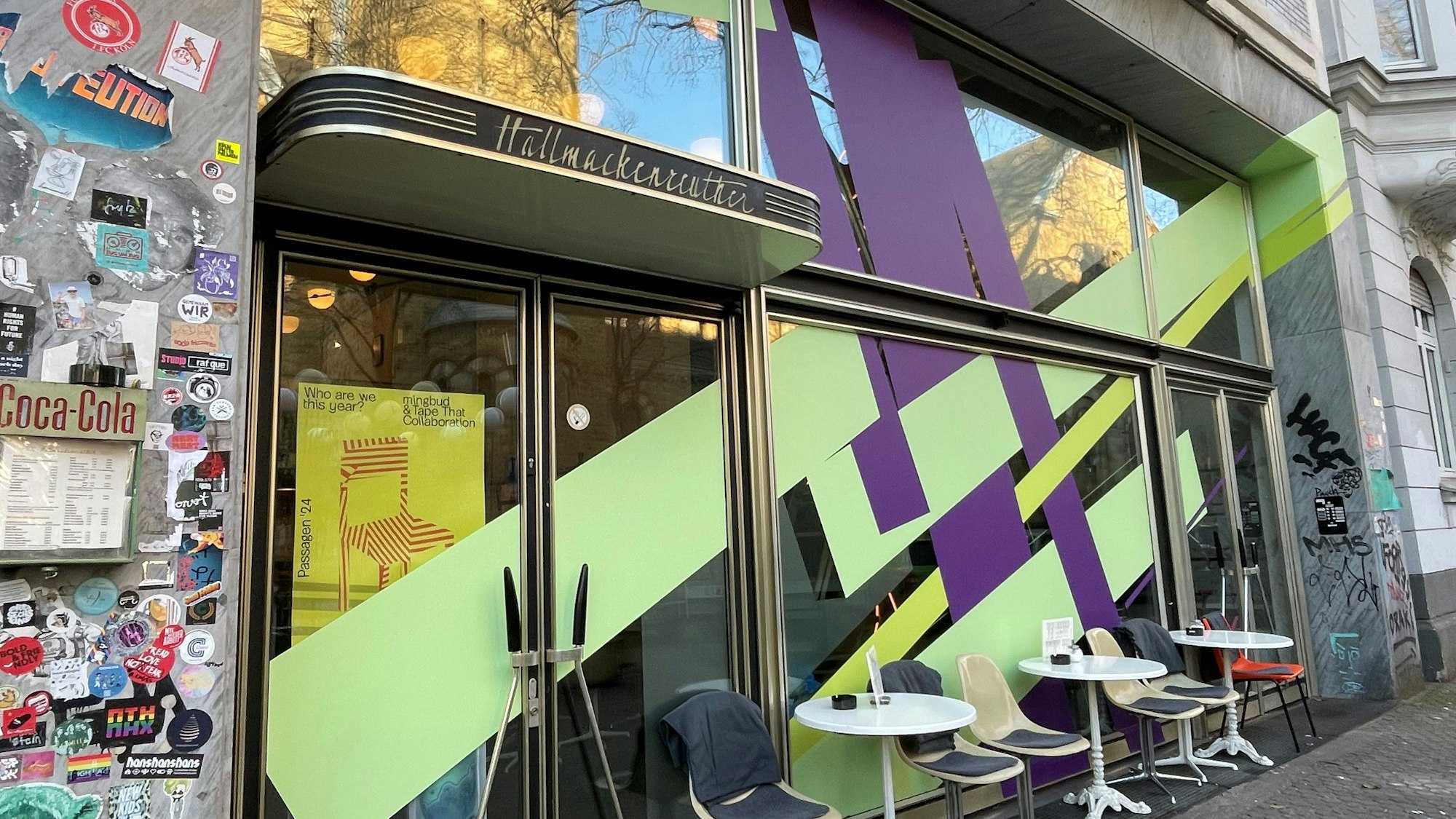 Die Front eines Cafés ist mit breiten lila und lindgrün-farbenen Streifen beklebt.