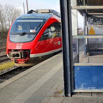 Ein Zug steht an einem Bahnsteig, im Wartehäuschen sind viele Scheiben zerschlagen.