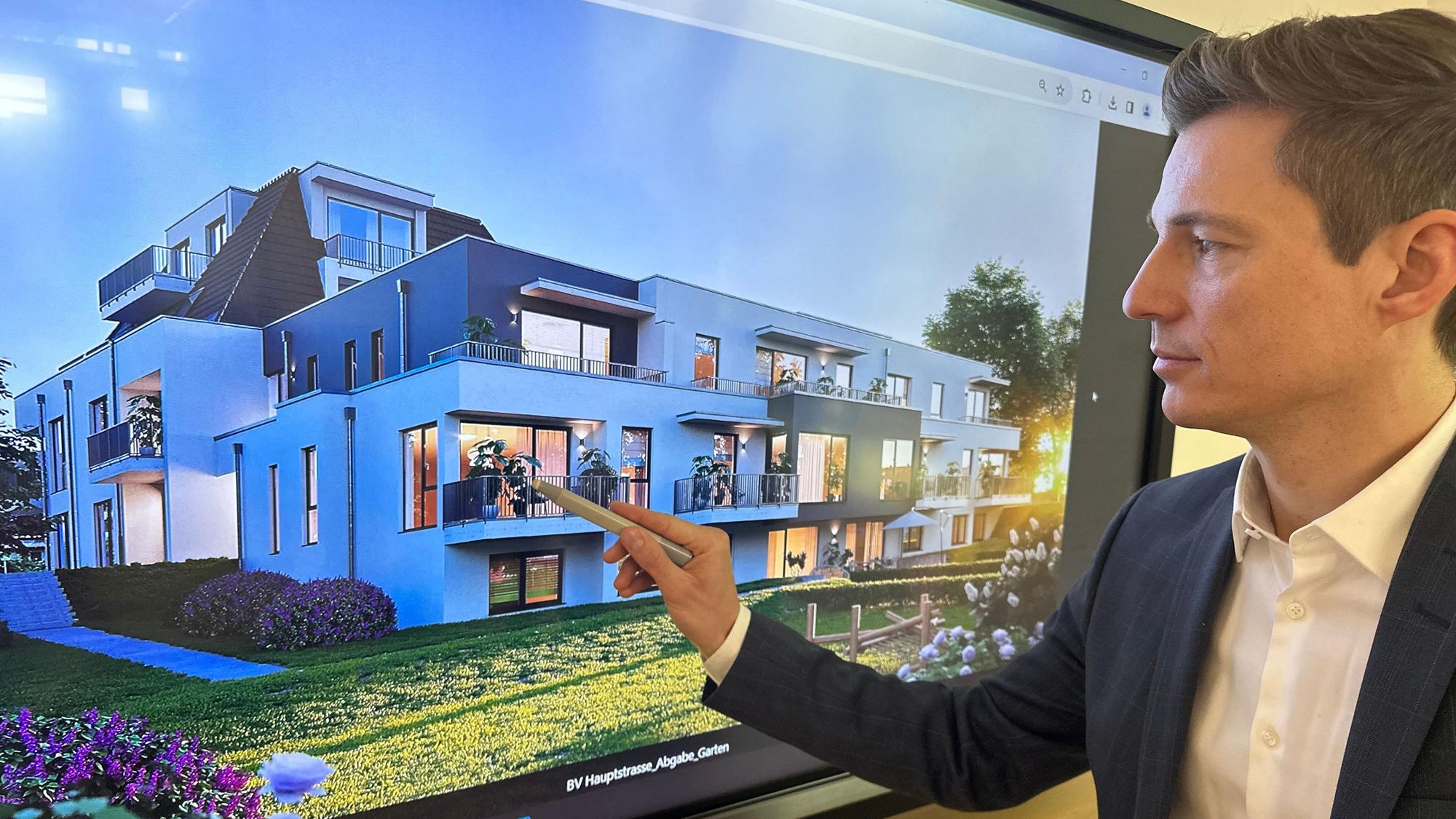 Fabioan Pleuser, Prokurist bei VR-Immobilien Bonn/Rhein-Sieg, vor dem Bild eines Neubaumehrfamilienhauses mit einem Flachdach.