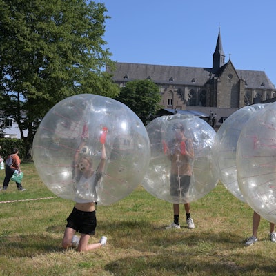 Ministrantentag Altenberg. Jugendliche laufen in großen, durchsichtigen Kugeln über die Wiese vor dem Altenberger Dom.