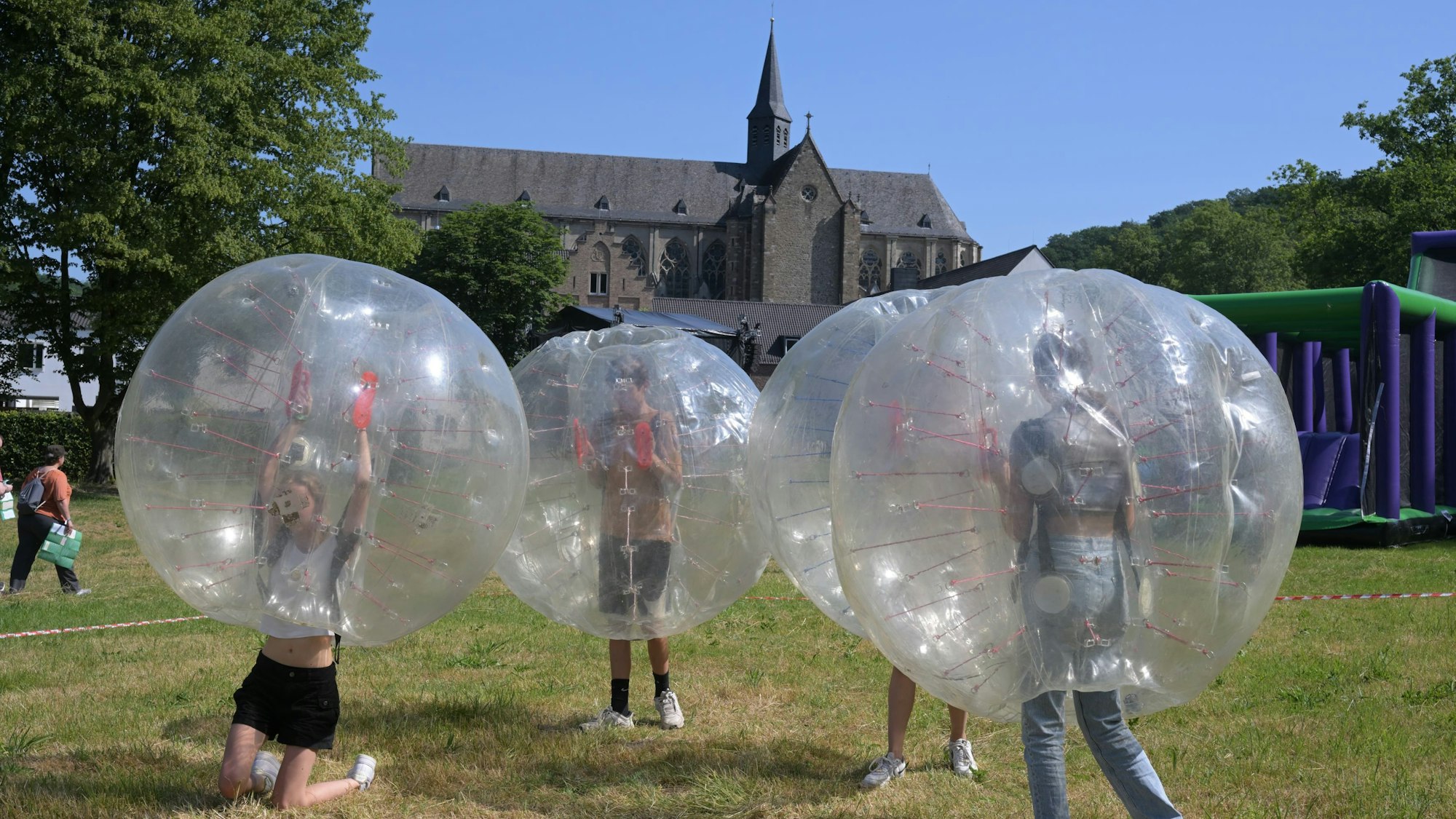 Ministrantentag Altenberg. Jugendliche laufen in großen, durchsichtigen Kugeln über die Wiese vor dem Altenberger Dom.