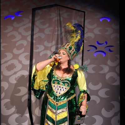 Eine Frau im glitzernden Kostüm trinkt ein Kölsch.