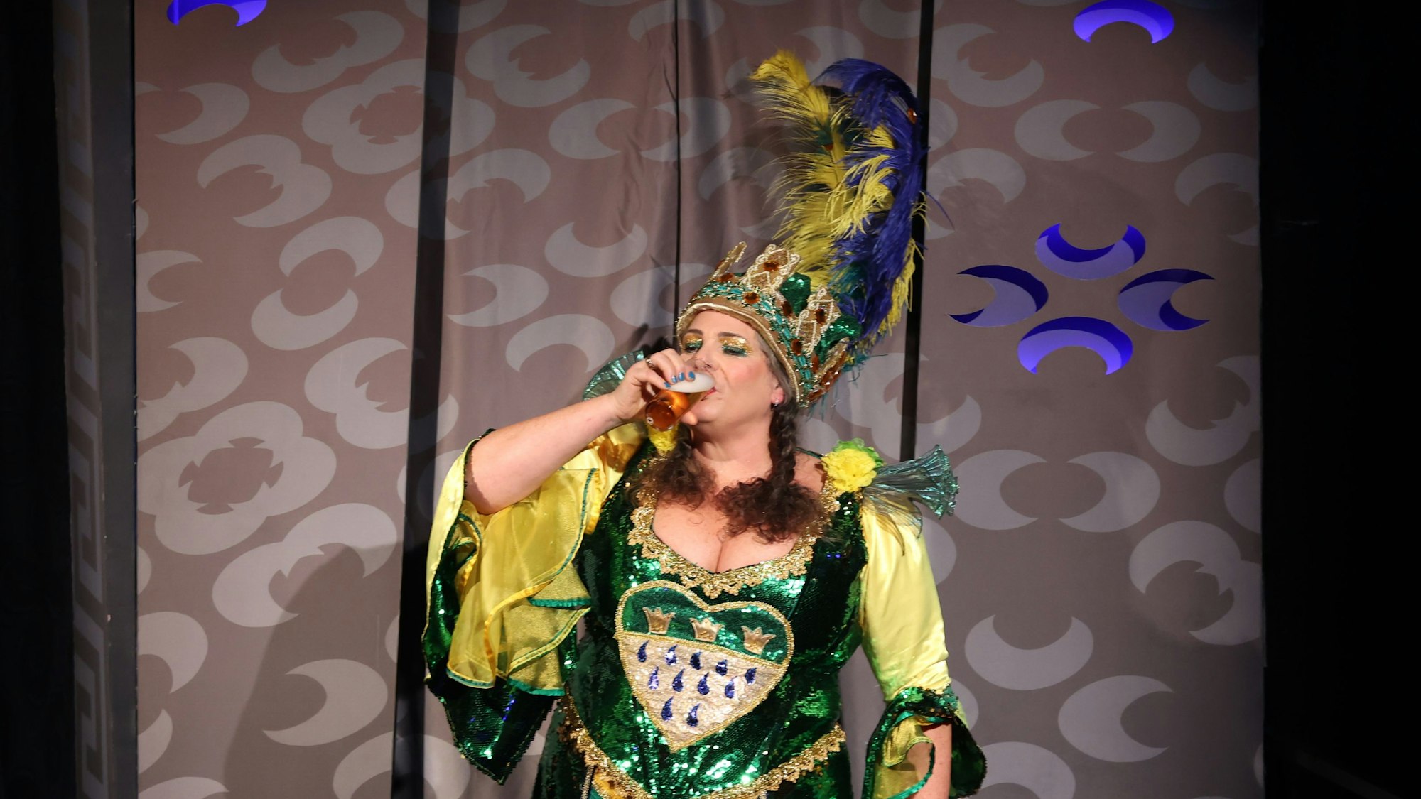 Eine Frau im glitzernden Kostüm trinkt ein Kölsch.