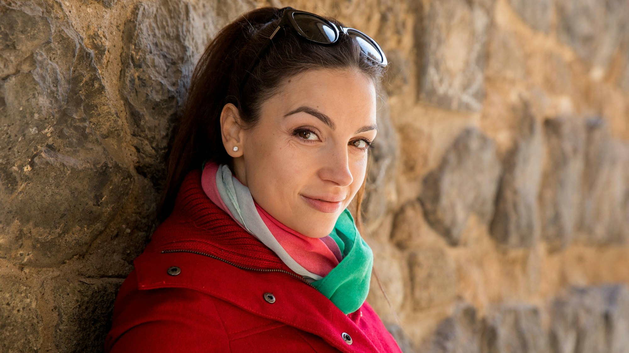 Olga Scheps lehnt an einer Mauer und schaut seitlich in die Kamera.