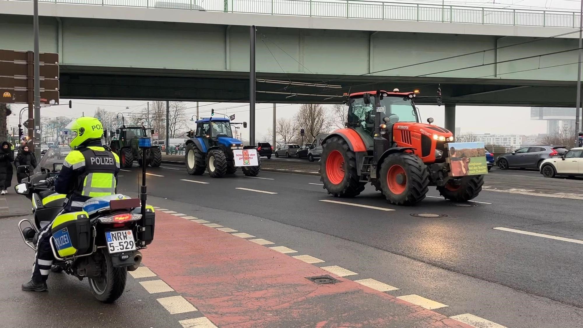 Ein Motorradpolizist steht am Traktoren-Weg.