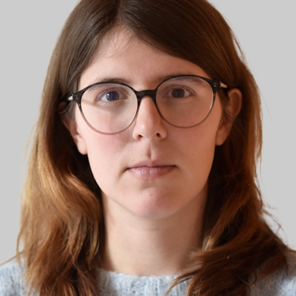 Ein Traktor und Strohballen mit Protest-Aufschriften stehen vor einem Feuer.