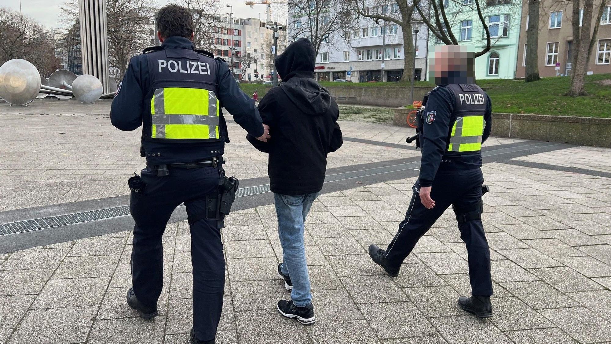 Zwei uniformierte Polizisten führen bei der Razzia am 10.01.2024 eine verdächtige Person auf dem Ebertplatz ab.