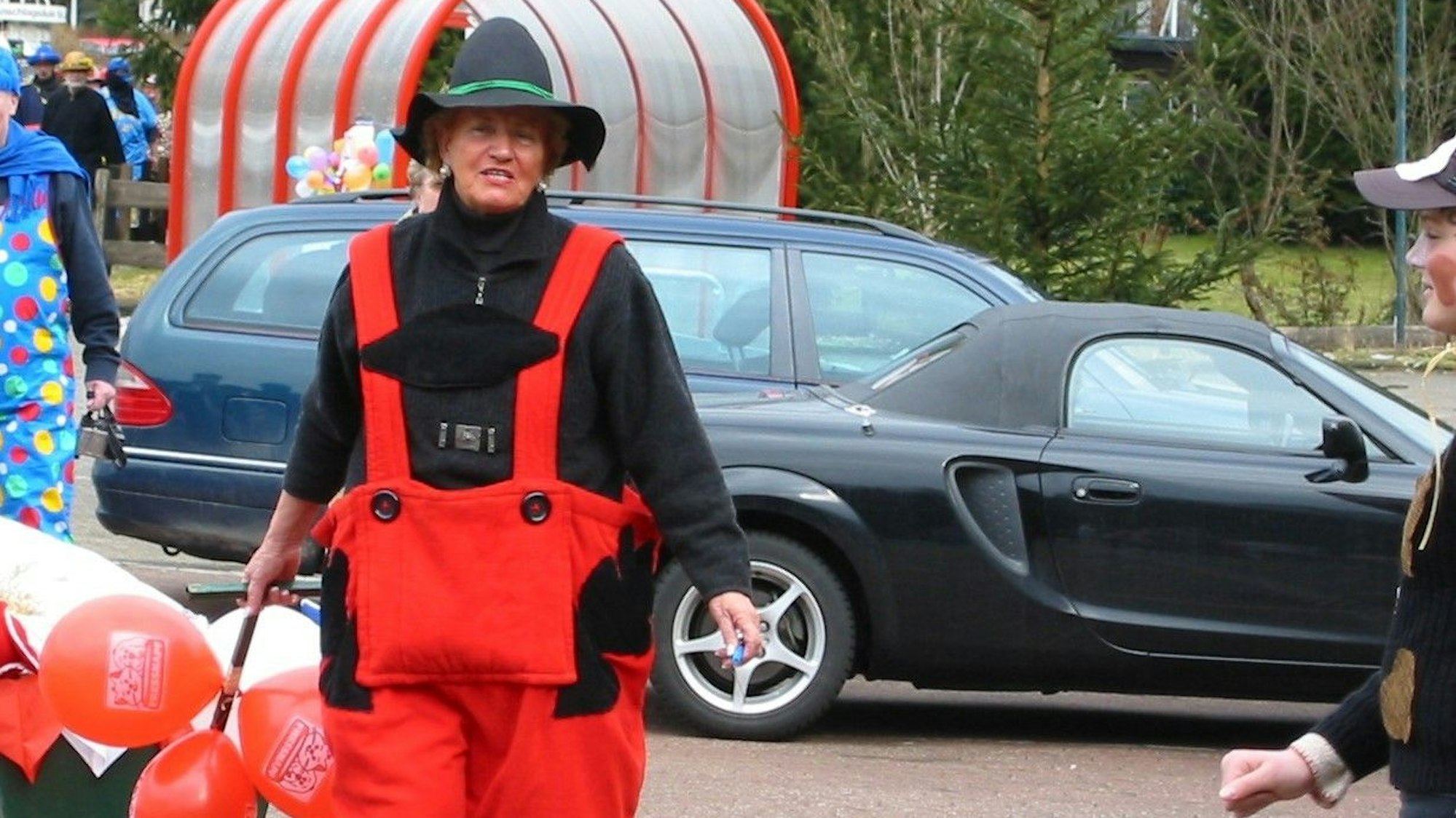 Eine verkleidete Frau zieht einen Bollerwagen hinter sich her.