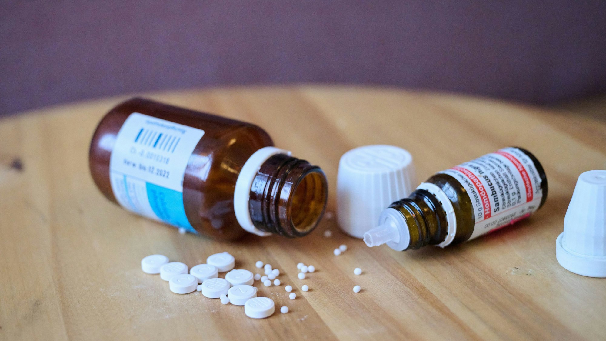 11.01.2024, Berlin: Illustration: Homöopathische Glasfläschchen, Kügelchen und Tabletten liegen auf einem Tisch. Foto: Annette Riedl/dpa +++ dpa-Bildfunk +++