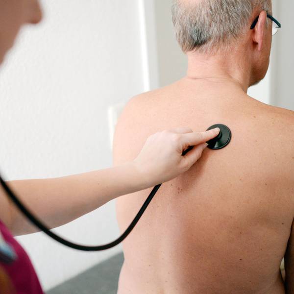 Eine Medizinerin untersucht einen Patienten mit einem Stethoskop.