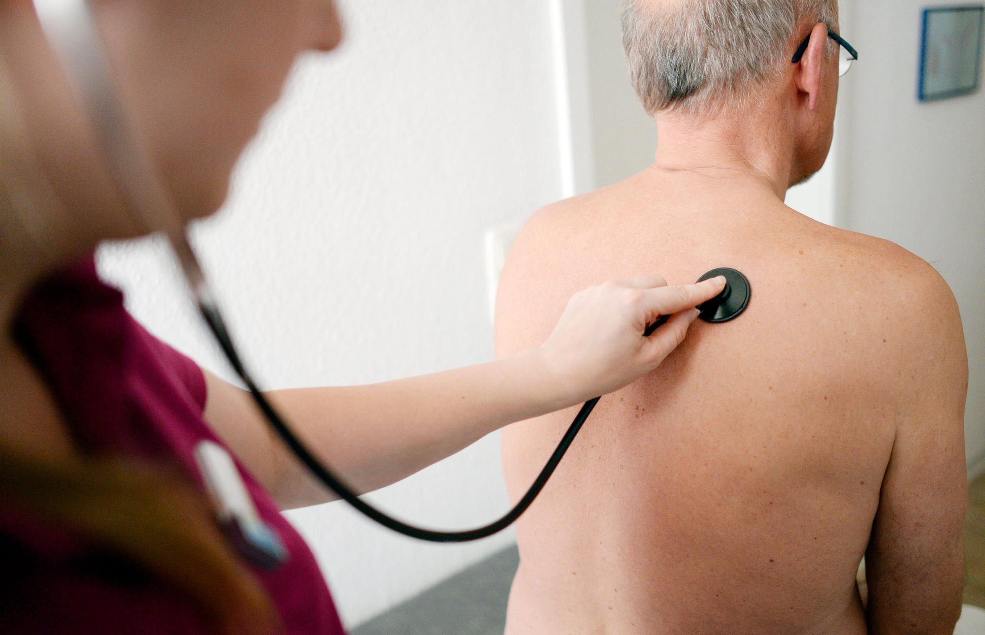 Eine Medizinerin untersucht einen Patienten mit einem Stethoskop.