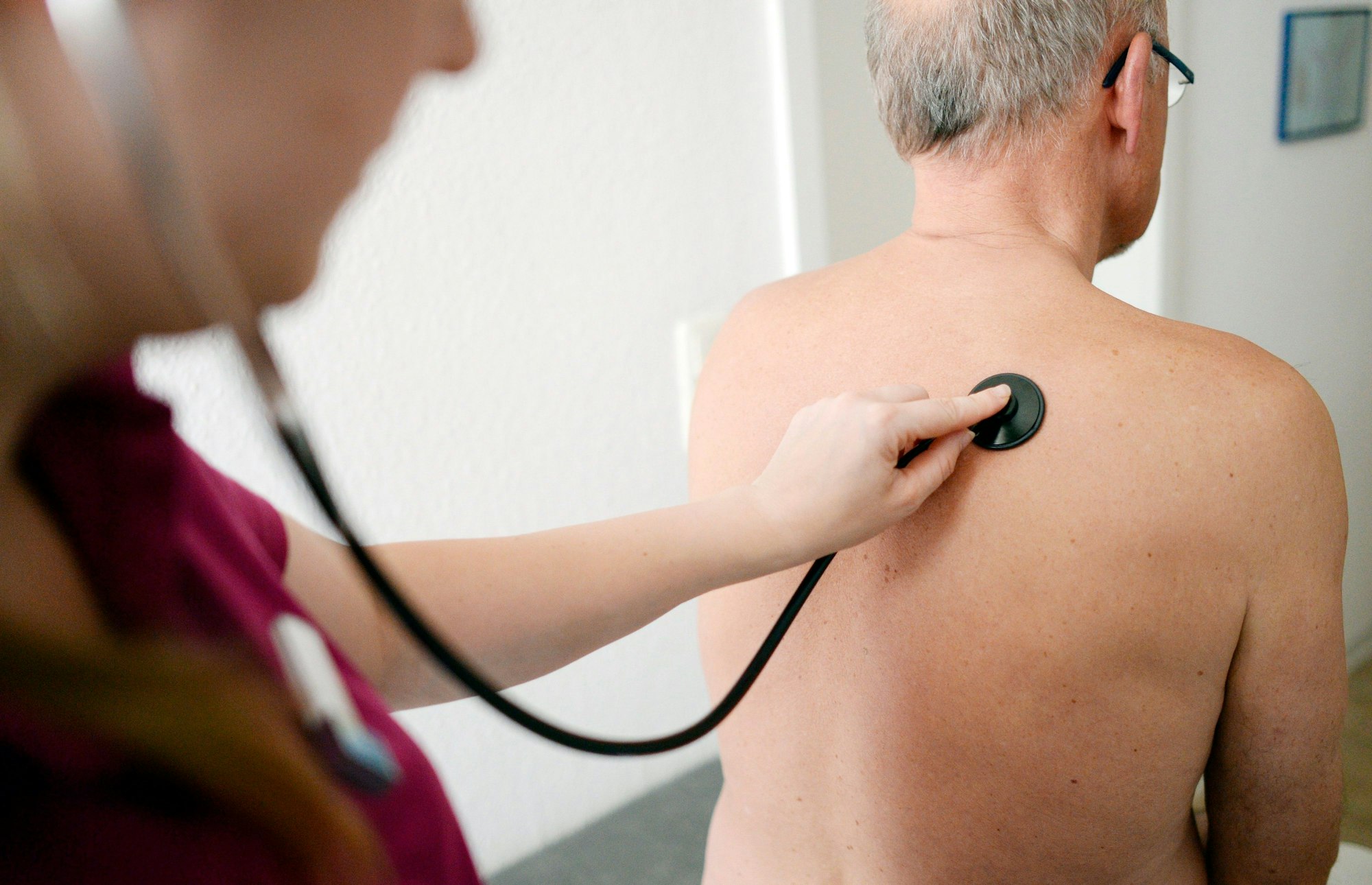 Eine Medizinerin untersucht einen Patienten mit einem Stethoskop.