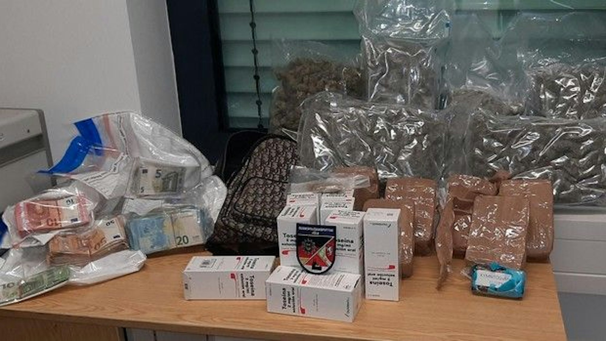 Auf einem Tisch sind Bargeld und Drogen ausgestellt.