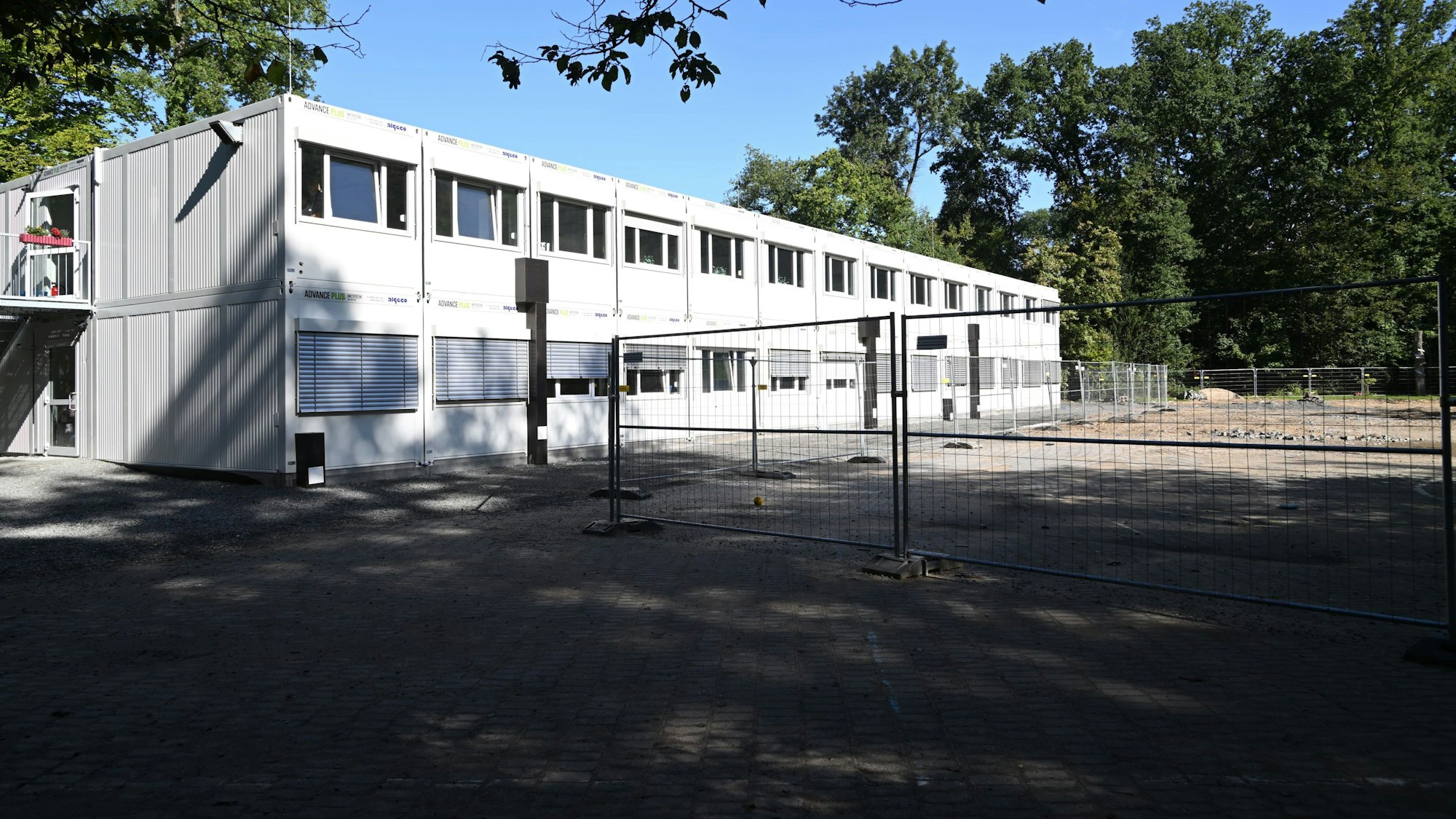 Ein großer Containerbau hinter Bauzäunen.