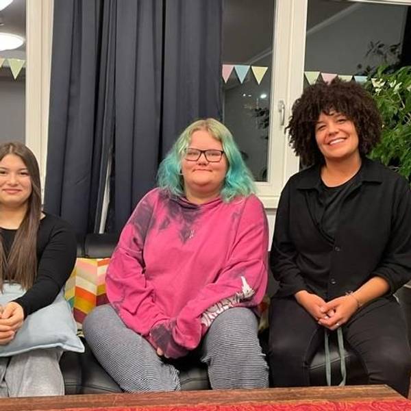 Die Bewohnerinnen der „WG Kompass“ der Diakonie Michaleshoven Dajana und Toni sitzen mit ihrer Erzieherin Alisha Anderson auf einem Sofa
