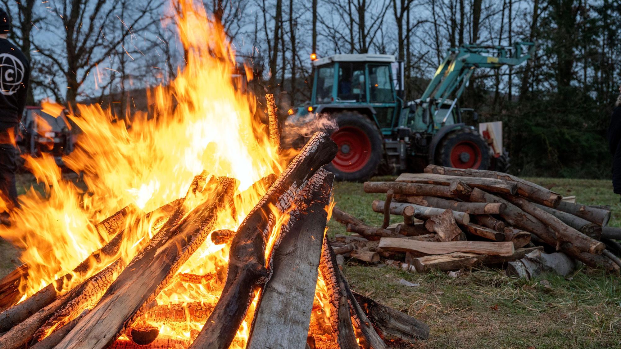 05.01.2024, Bayern, Burgpreppach: Ein Schlepper fährt an einem Feuer vorbei. An der Bundesstraße 303 in Burgpeppach sowie rund 14 weiteren Orten in Franken demonstrieren Landwirte am Freitagabend mit Mahnfeuern unter dem Motto "Franken in Flammen" gegen geplante Kürzungen der Agrardiesel-Subventionen und die Abschaffung von Kfz-Steuererleichterungen in der Land- und Forstwirtschaft. Foto: Pia Bayer/dpa +++ dpa-Bildfunk +++