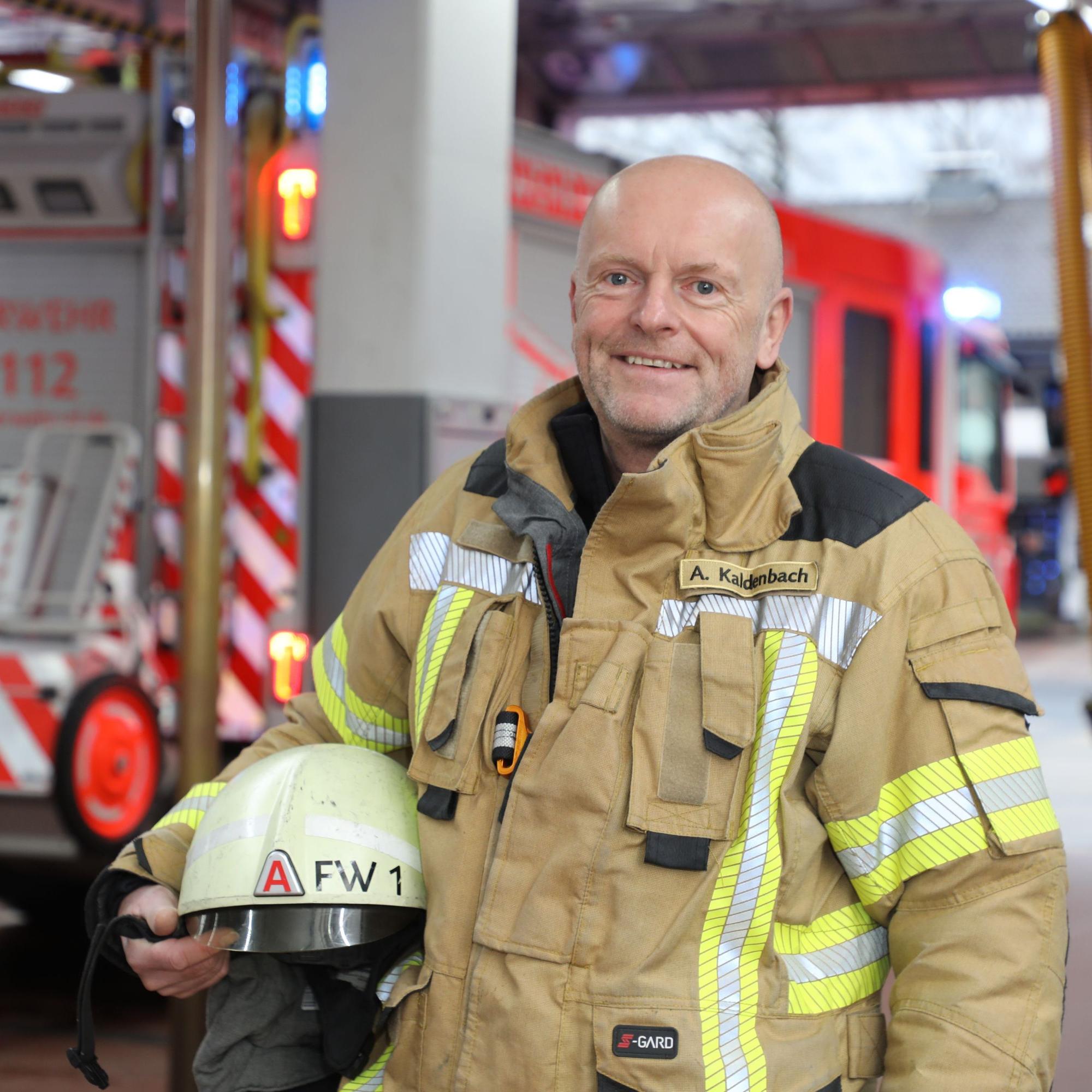 Andreas Kaldenbach steht mit Feuerwehreinsatzkleidung in der Fahrzeughalle der Feuerwehrwache an der Paffrather Straße in Bergisch Gladbach.