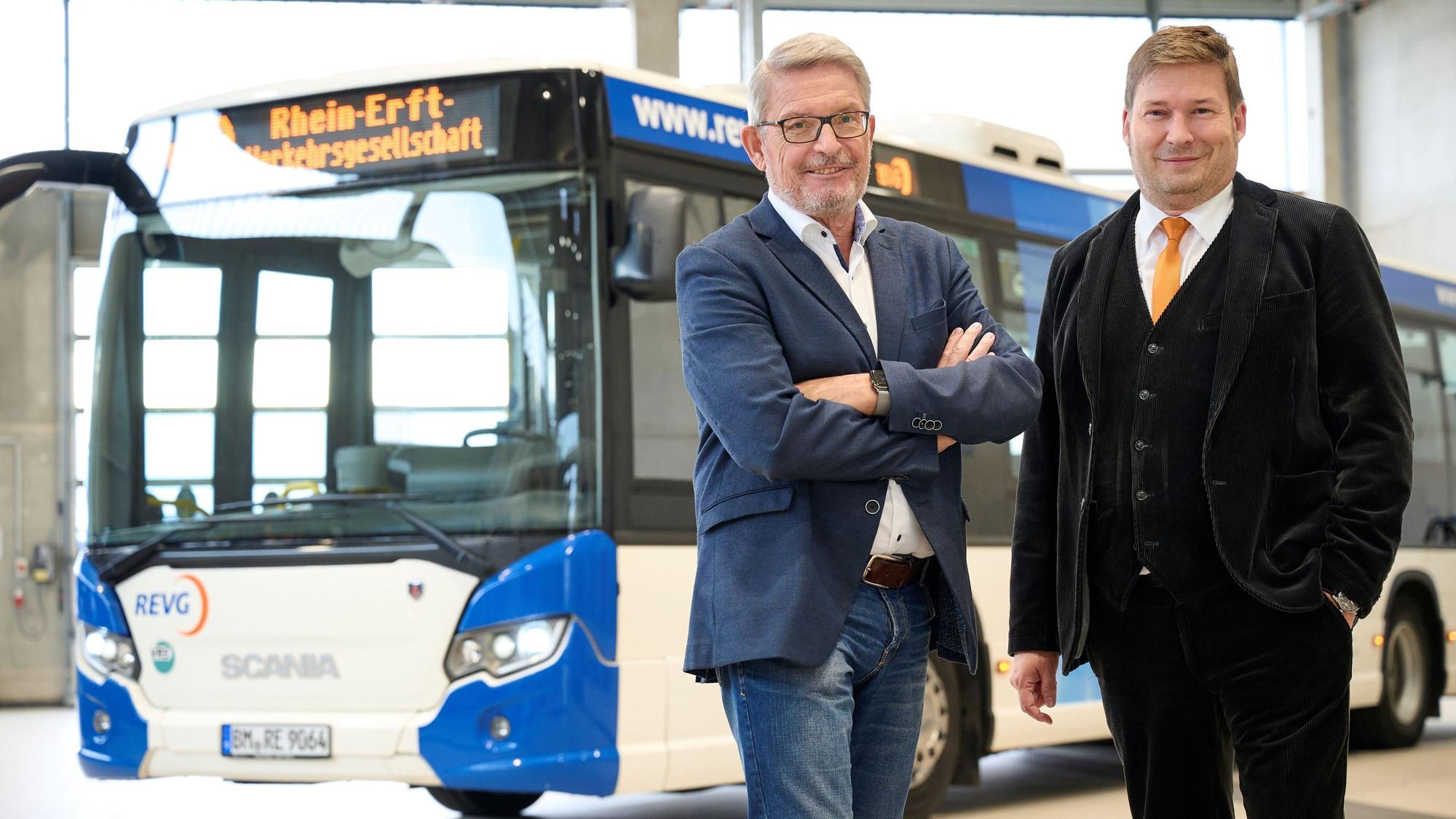 Die REVG-Geschäftsführer Walter Reinarz und Martin Gawrisch stehen vor einem blau-weißen Linienbus.