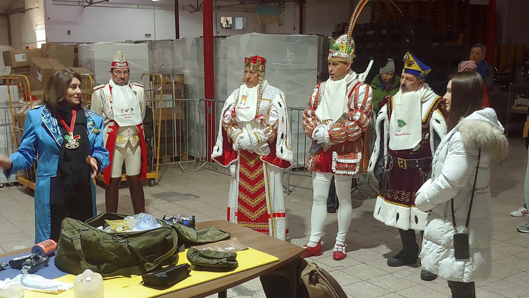 Linda Mai (blau) vom Verein Blau-Gelbes-Kreuz führt das Kölner Dreigestirn durch die Lagerhalle in Bayenthal.