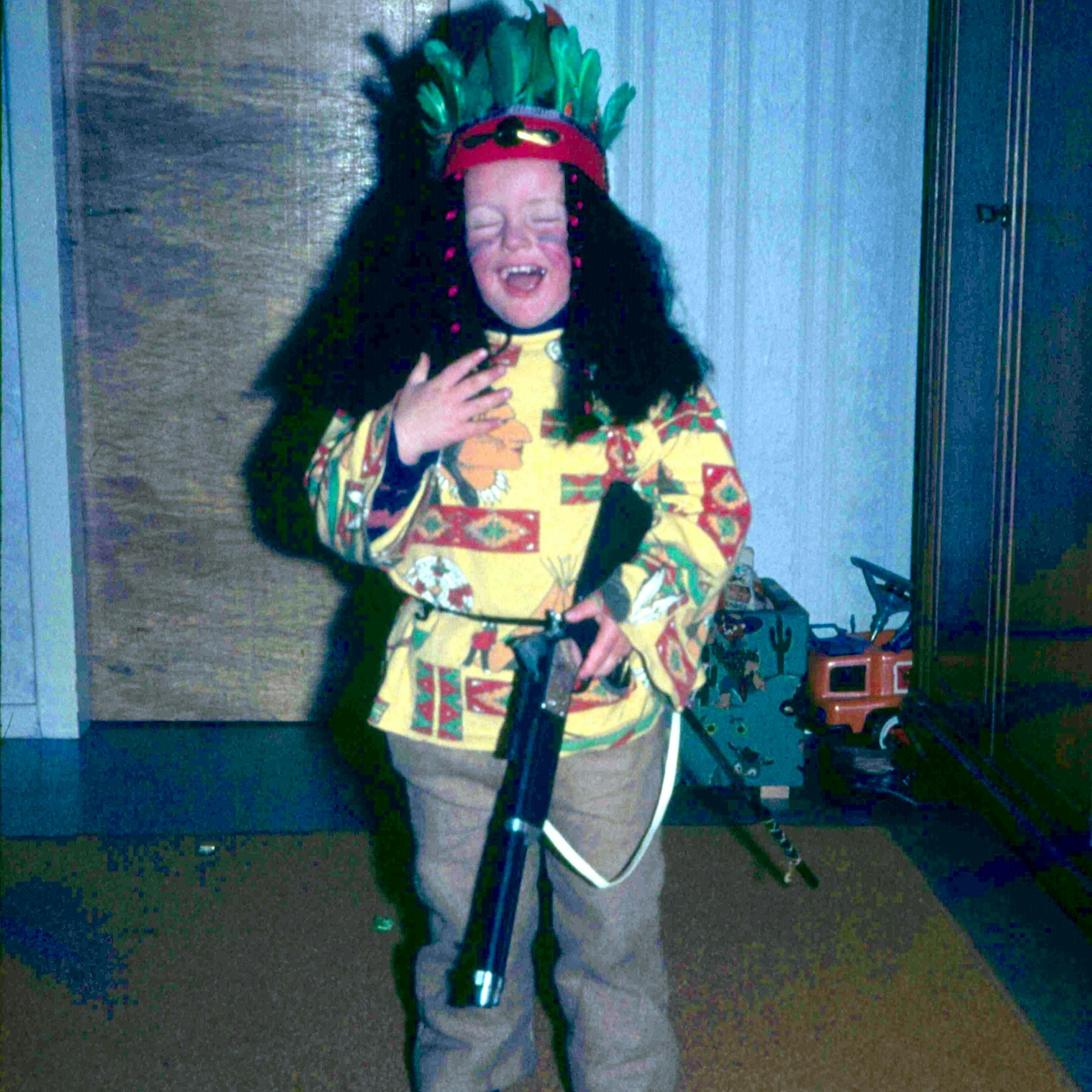 Ein Kind steht als Indianer verkleidet in einem Kinderzimmer.