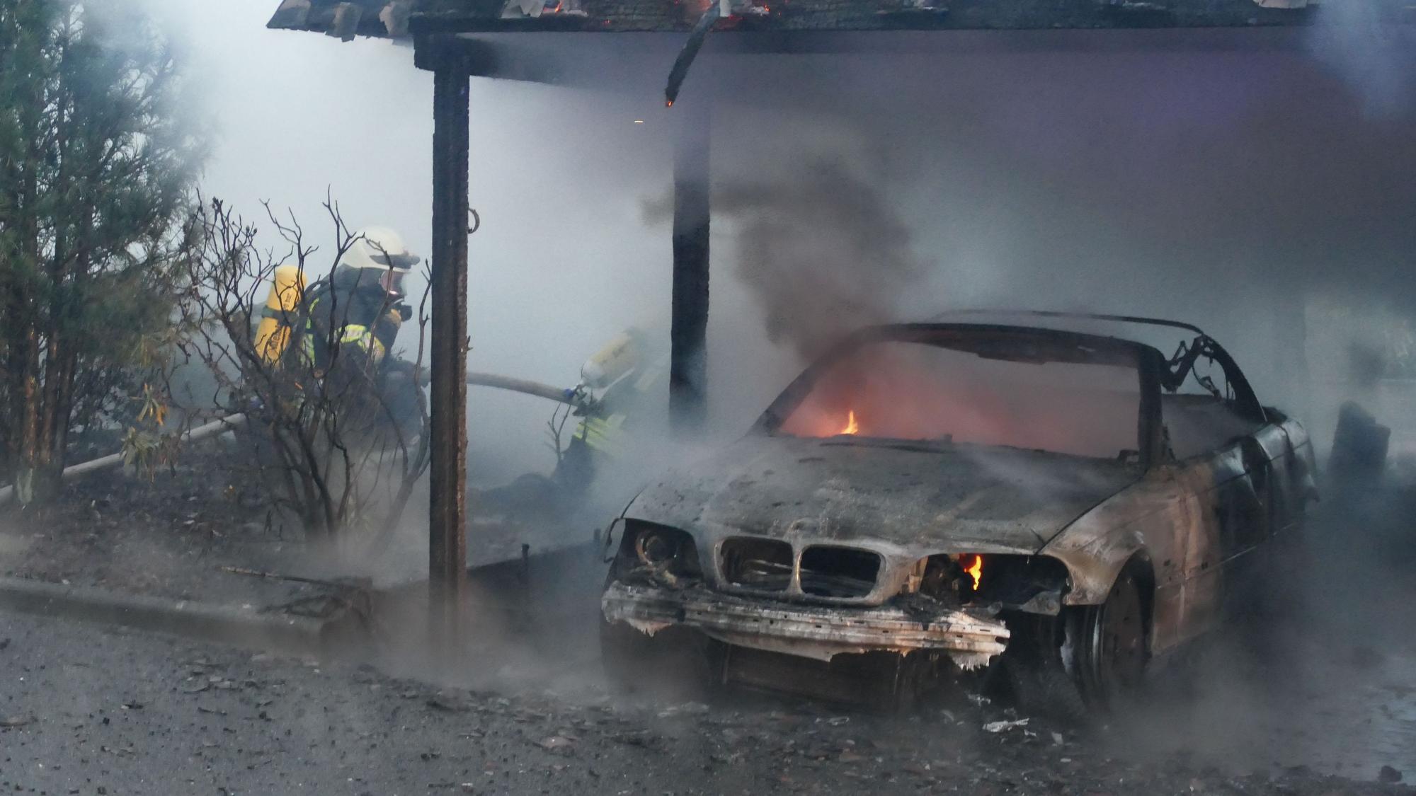 Ein ausgebranntes Auto steht unter einem Carport.