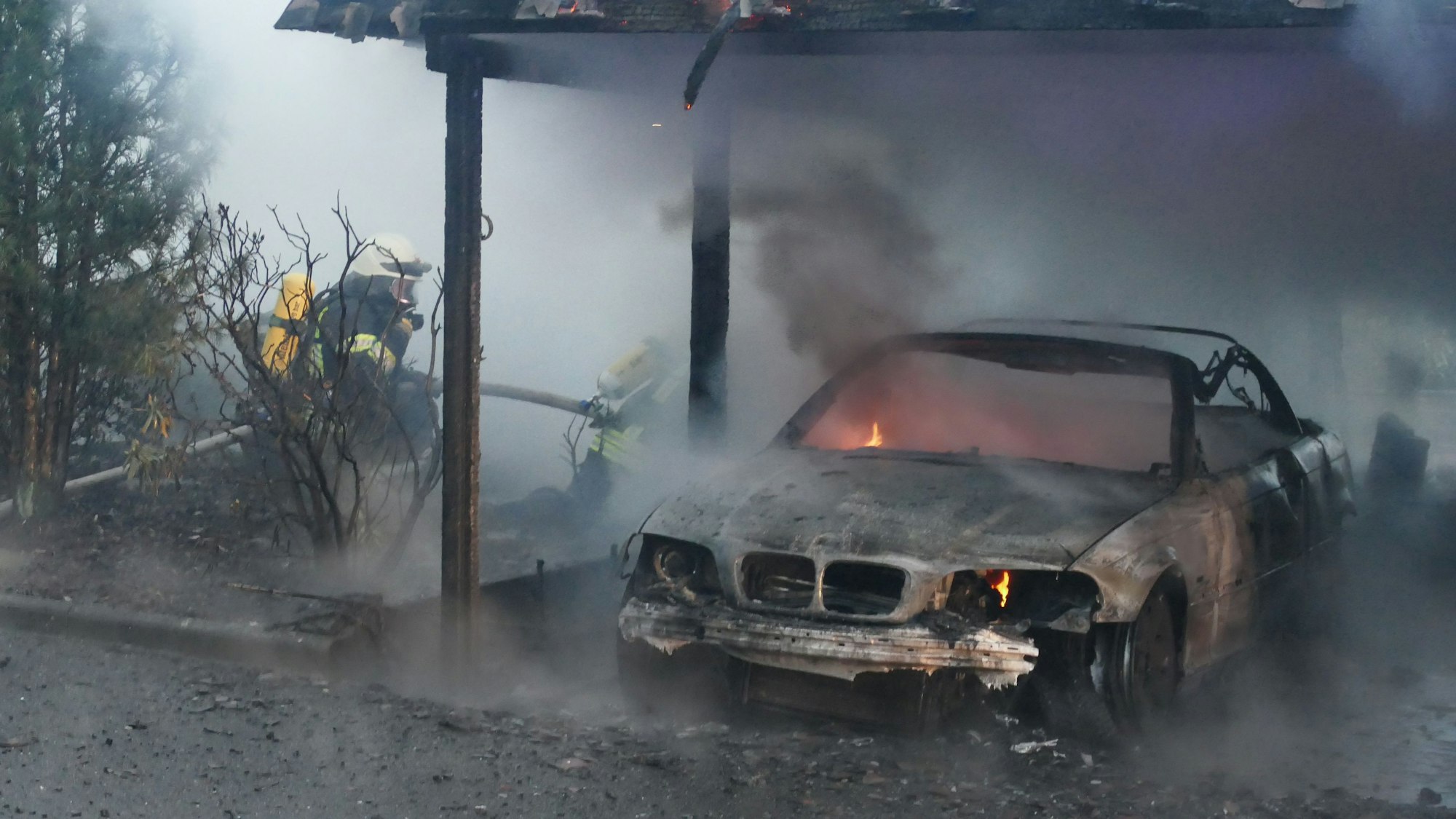 Ein ausgebranntes Auto steht unter einem Carport.