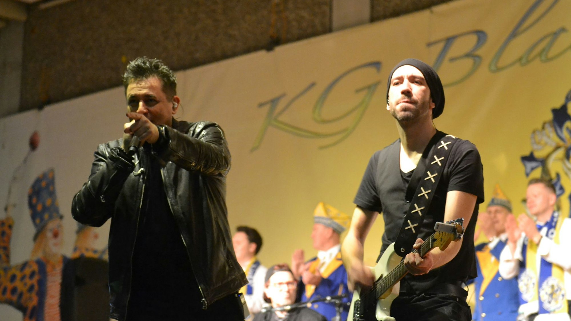 Der Sänger der Gruppe Domstürmer, Micky Nauber, auf der Karnevalsbühne in Weilerswist, neben ihm ein Gitarrist der Band, im Hintergrund Mitglieder des Elferrats.