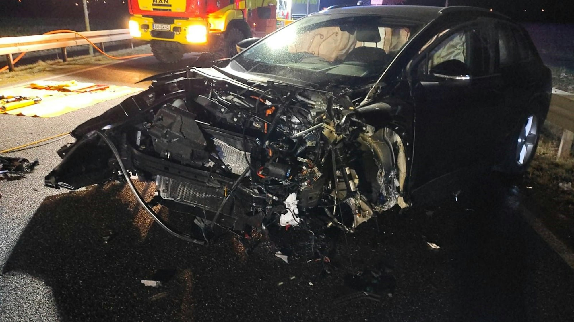 Ein zerstörter schwarzer Audi steht auf einer Landstraße.