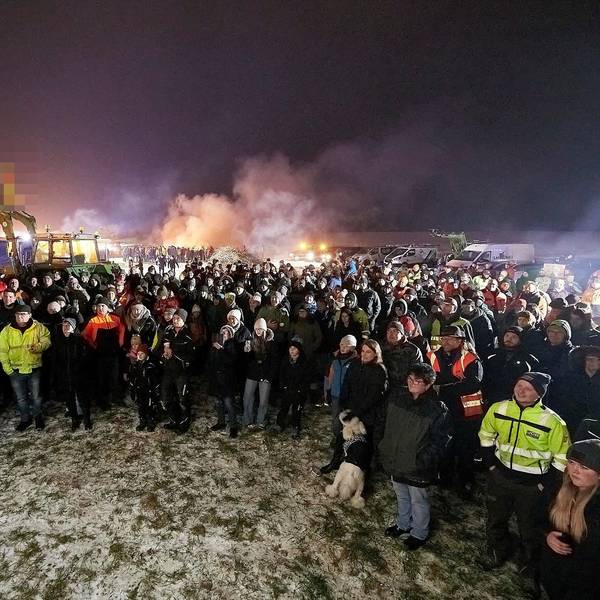 Zahlreiche Menschen stehen auf einem Feld zusammen. An einem Traktor im Hintergrund waren Deutschland-Fahnen kopfüber angebracht. Der Landwirt erhielt eine Ordnungswidrigkeiten-Anzeige der Polizei, weil die Flaggen den Bundesadler zeigten und dieses Hoheitszeichen amtlichen Stellen des Bundes vorbehalten ist.