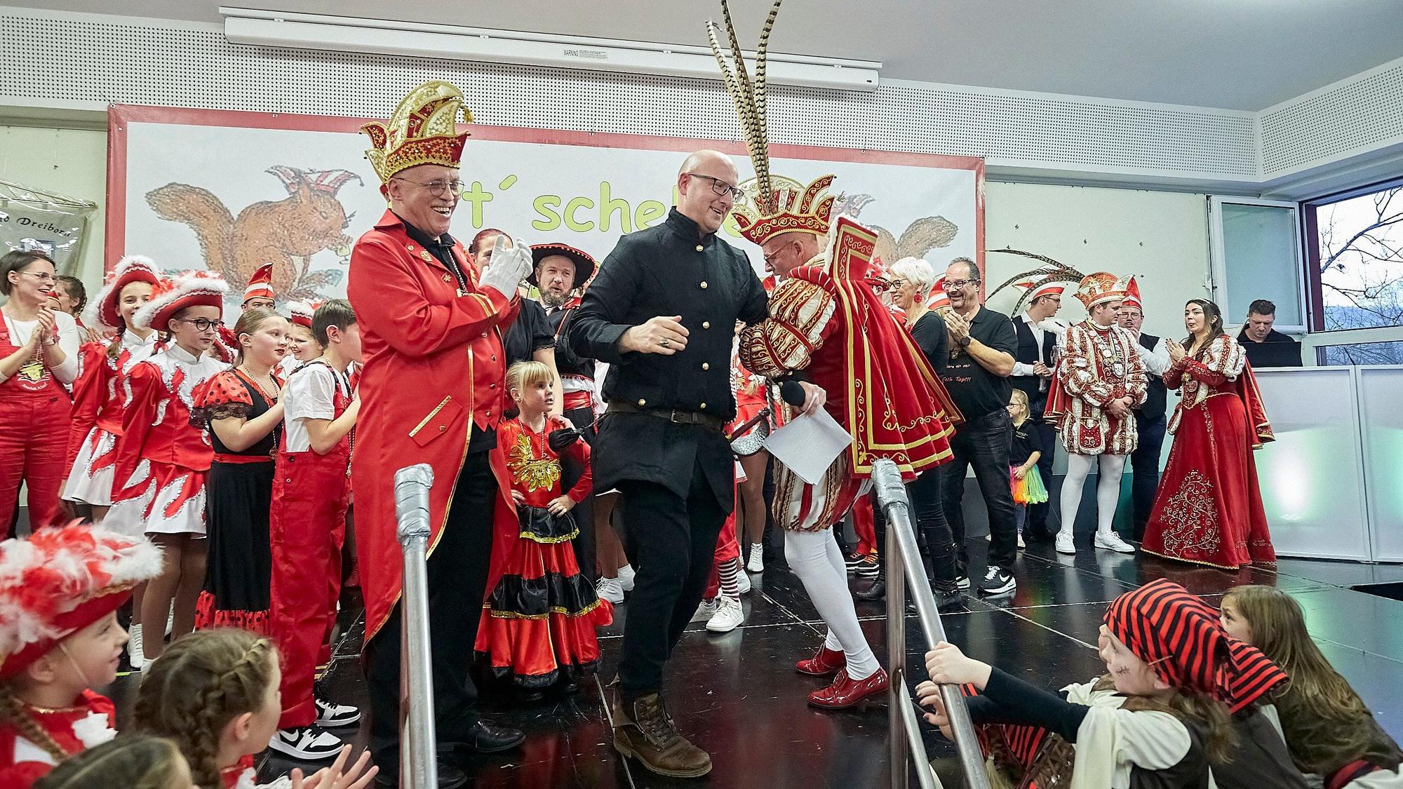 Bürgermeister Ingo Pfennings und der Gemünder Prinz Carlos Emunds tanzen auf der Bühne, auf der zahlreiche weitere Karnevalisten zu sehen sind.