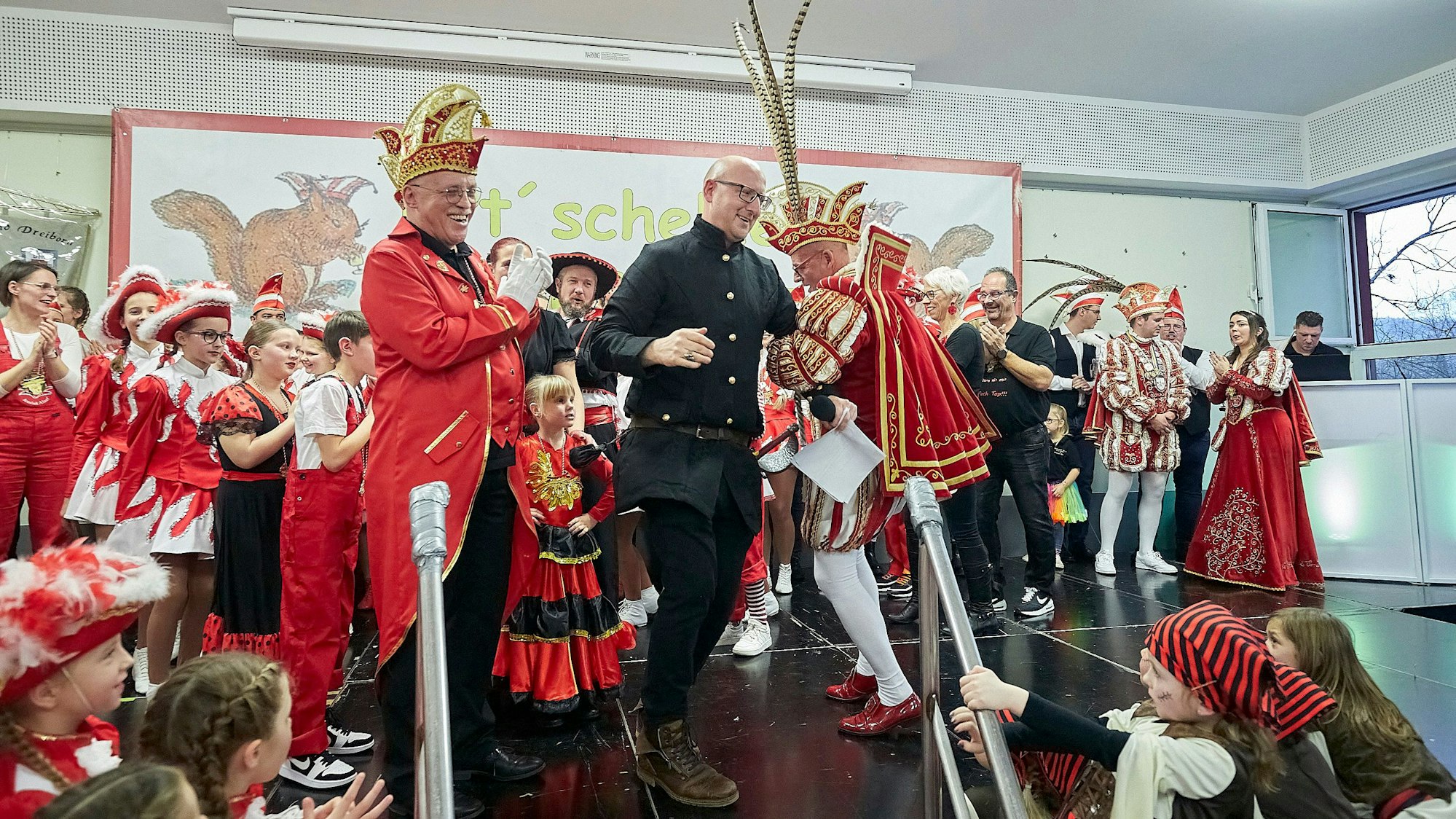 Bürgermeister Ingo Pfennings und der Gemünder Prinz Carlos Emunds tanzen auf der Bühne, auf der zahlreiche weitere Karnevalisten zu sehen sind.
