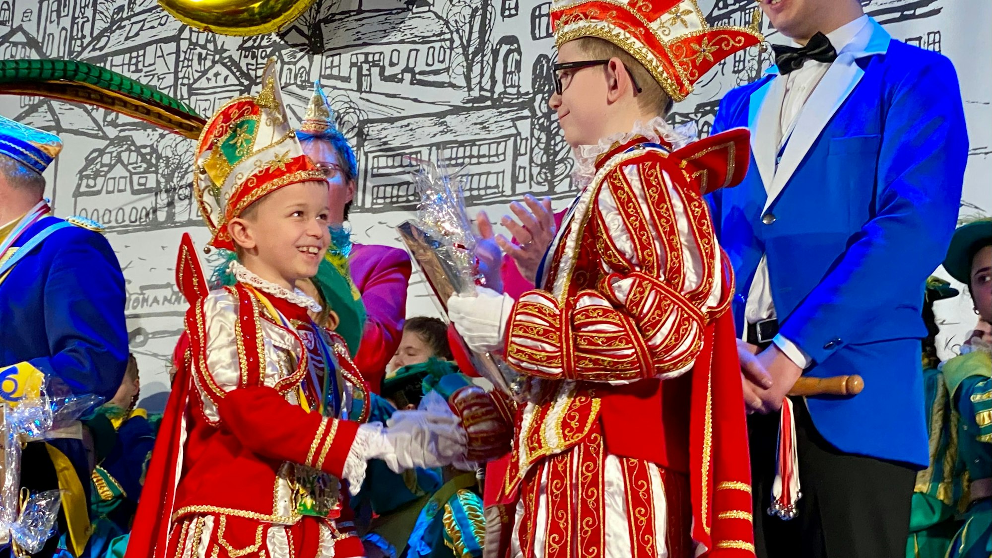 Zwei Jungen im Prinzen-Ornat schütteln einander die Hände.